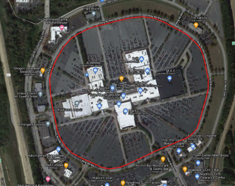 Satellite image of a shopping mall surrounded by parking lots with a red outline around the parking lots encompassing the main building as well.